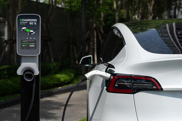 EV electric car charging in green sustainable city outdoor garden in summer. Urban sustainability...