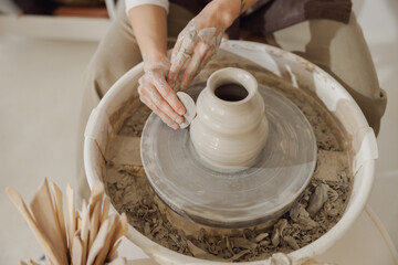 Close up of artisan's hands shaping clay bowl in pottery studio. Pottery art and creativity