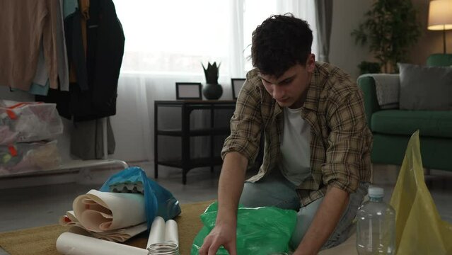 young man recycle at home sorting waste plastic paper and glass