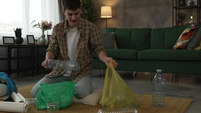 young man recycle at home sorting waste plastic paper and glass