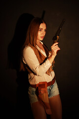 Beautiful young woman with old wild west revolver low key portrait