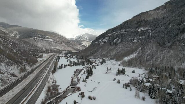 Aerial footage from a drone showcases Highway 70 cutting through the breathtaking snow-capped mountains of Vail, Colorado, offering a stunning view of the scenic landscape