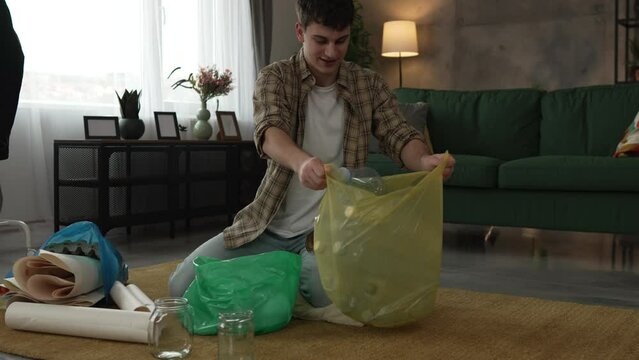 young man recycle at home sorting waste plastic paper and glass