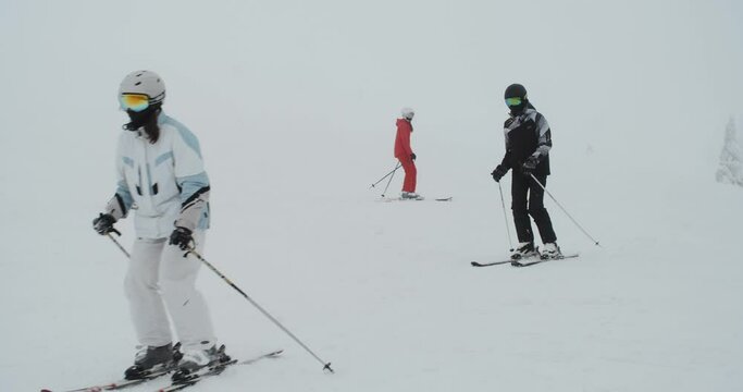 A group of skiers training and skiing on a snowy slope on a foggy day