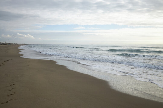 xBeach with Waves and Person Fishing Under Cloudy Sky in Ladispoli Lazio Italy