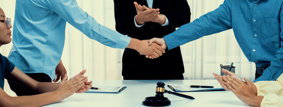 Lawyer acting as legal mediator successfully broke a compromise and seal with handshake between two parties to resolve business dispute through negotiation at law firm office. Panorama Rigid