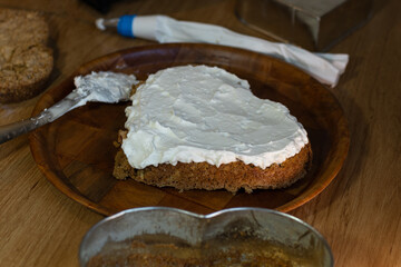 Horizontal photograph without people, of the preparation of a cake, where there is a handmade cake with cream on a kitchen table
