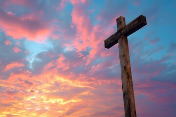 A wooden cross silhouetted against a vibrant sunset with clouds scattered across the colorful sky