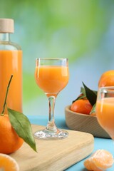 Delicious tangerine liqueur and fresh fruits on light blue table