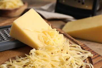 Grated and whole pieces of cheese on wooden table, closeup