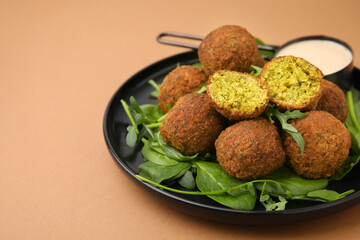 Delicious falafel balls, herbs and sauce on pale brown, space for text