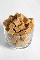 Brown sugar cubes on white table, closeup