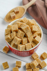 Bowl and spoon with brown sugar cubes, closeup