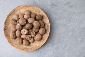 Wooden board with nutmegs on light grey table, top view. Space for text