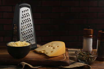 Cheese, grater and spices on wooden table