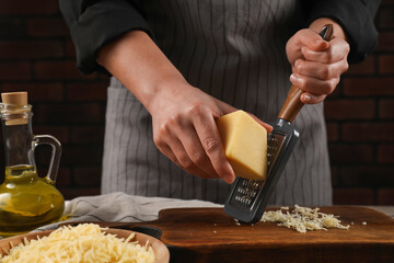 Woman grating cheese at wooden table, closeup