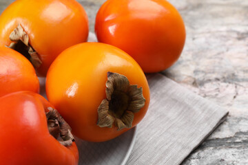 Delicious ripe persimmons on grey textured table, closeup