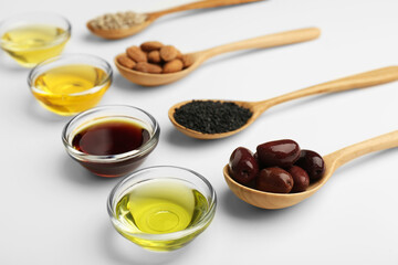 Vegetable fats. Different cooking oils in bowls and spoons with ingredients on white background