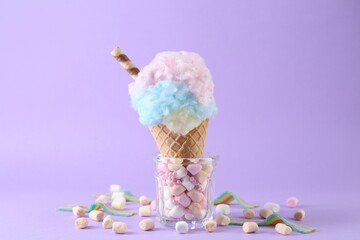 Sweet cotton candy in waffle cone and marshmallows on purple background