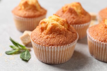 Delicious sweet muffins and brown sugar on light grey textured table, closeup