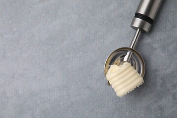 Tasty butter curl in spoon on light grey table, top view. Space for text