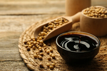 Obraz na płótnie Canvas Soy sauce in bowl and beans on wooden table, closeup. Space for text
