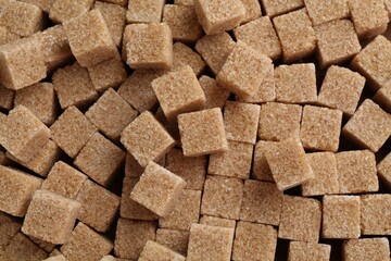 Brown sugar cubes as background, top view