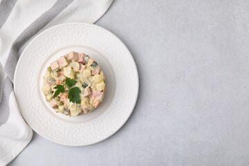 Tasty Olivier salad with boiled sausage on light grey table, top view. Space for text
