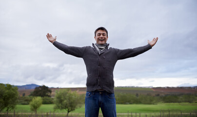 Man, portrait and happiness with freedom or sky for relax, travel and winter adventure on holiday or vacation. Person, tourist and face with smile in nature, outdoor and countryside with wellness