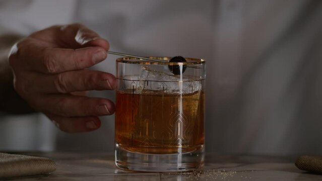 Bartender places a cherry on top of an old fashioned