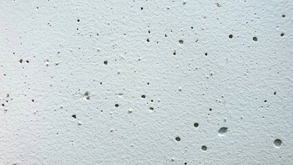 The white cement walls are deteriorating, the paint is peeling off and there are holes on the walls.