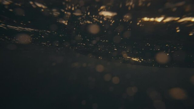 SLOW MOTION UNDERWATER, LENS FLARE: Crystal clear ocean wave breaking over the camera at golden sunset in the Caribbean. Cinematic shot of a tube wave splashing over camera filming the summer sunset.