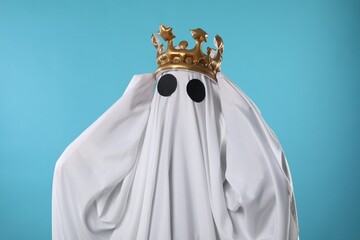 Person in ghost costume and luxurious crown on light blue background