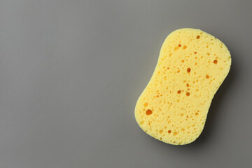 New yellow sponge on grey background, top view. Space for text
