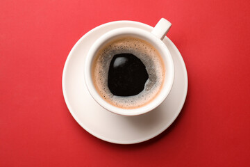 Fresh coffee in cup on red background, top view