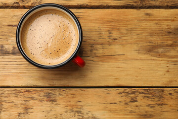 Cup of aromatic coffee on wooden table, top view. Space for text
