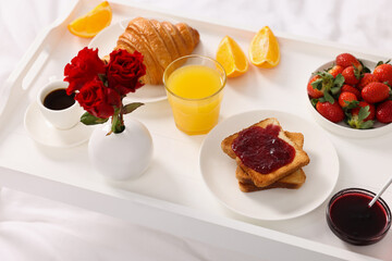 Tray with delicious breakfast on bed, closeup