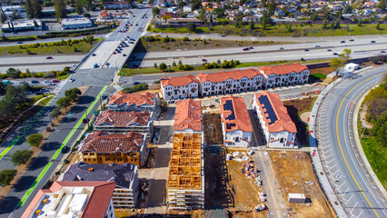 Aerial view of a residential buildings construction site adjacent to highway and established...