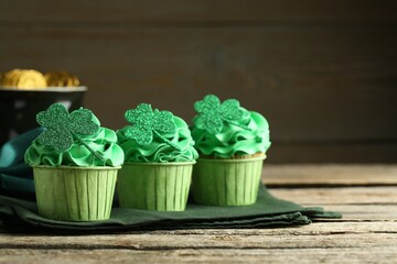 St. Patrick's day party. Tasty cupcakes with clover leaf toppers and green cream on wooden table,...