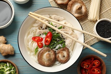 Delicious ramen with meat and ingredients on light blue wooden table, flat lay. Noodle soup