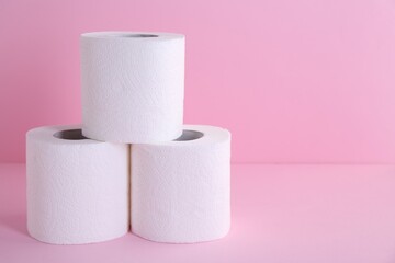 Soft toilet paper rolls on pink background, closeup. Space for text