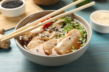 Delicious ramen with meat and ingredients on light blue wooden table, closeup. Noodle soup