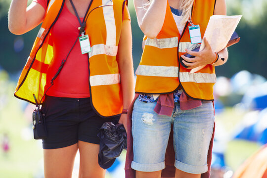 Hands, festival and event security with people outdoor on campsite together for safety or crowd control. Camping, concert or reflective vest with person and partner on grass for community patrol