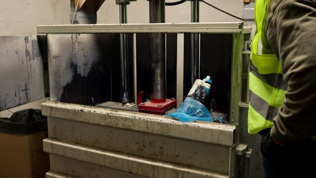 Special garbage compactor machine presses large garbage bag for waste disposal at waste recycling station