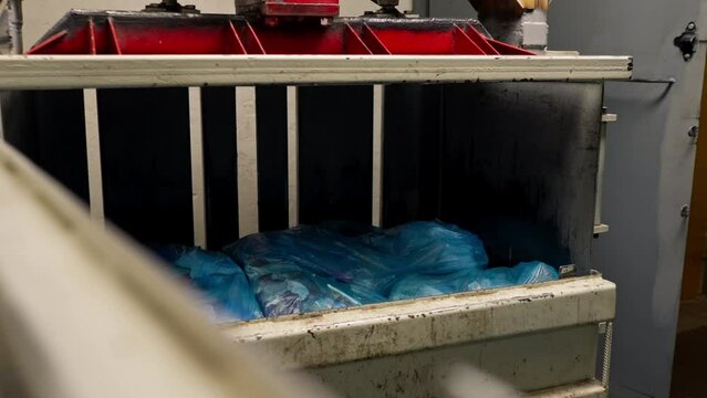 Special garbage compactor machine presses large garbage bag for waste disposal at waste recycling station