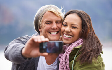 Selfie, phone screen and couple hug in nature for travel, freedom or road trip adventure together. Smartphone, photography and people with love outdoor for camping, journey or social media memory