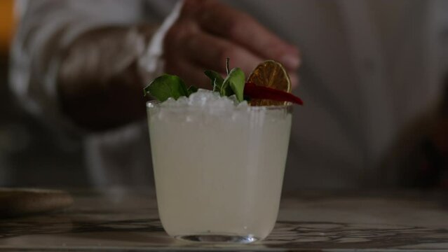 Bartender pushes a margarita towards camera