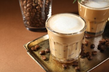 Refreshing iced coffee with milk in glasses on brown table, closeup