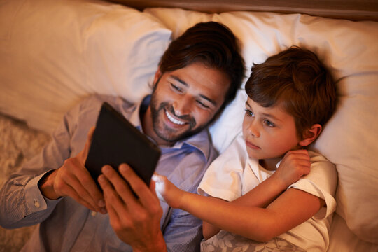 Bedroom, father and son with tablet, night and family with ebook and connection with social media. Dad, house and boy with technology and bedtime story with lights and bonding together with hobby