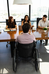 Rear view of a disable man in a wheelchair getting interviewed for a job